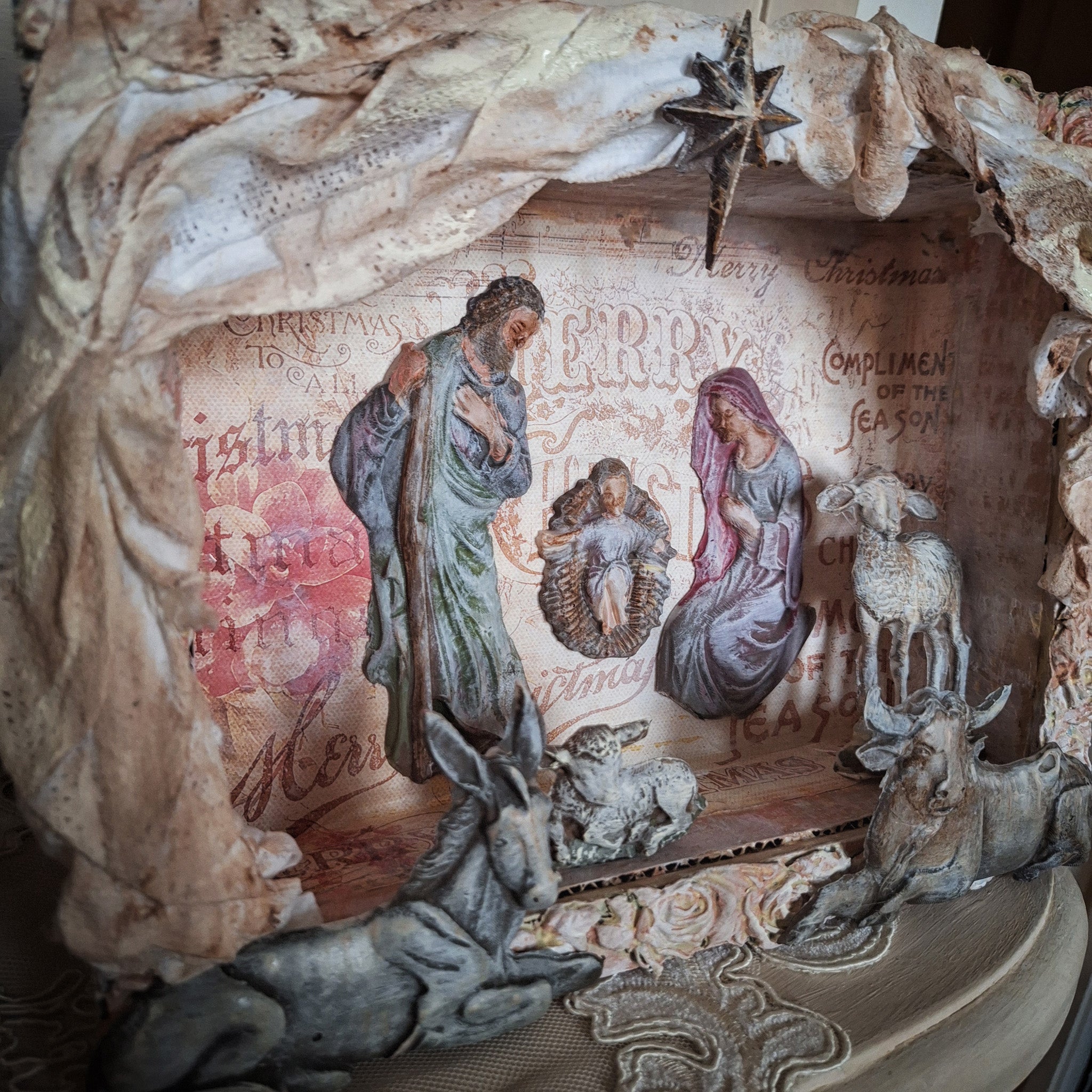 A shadow box craft features Decoupage Queen's Holy Family silicone mold castings in it.