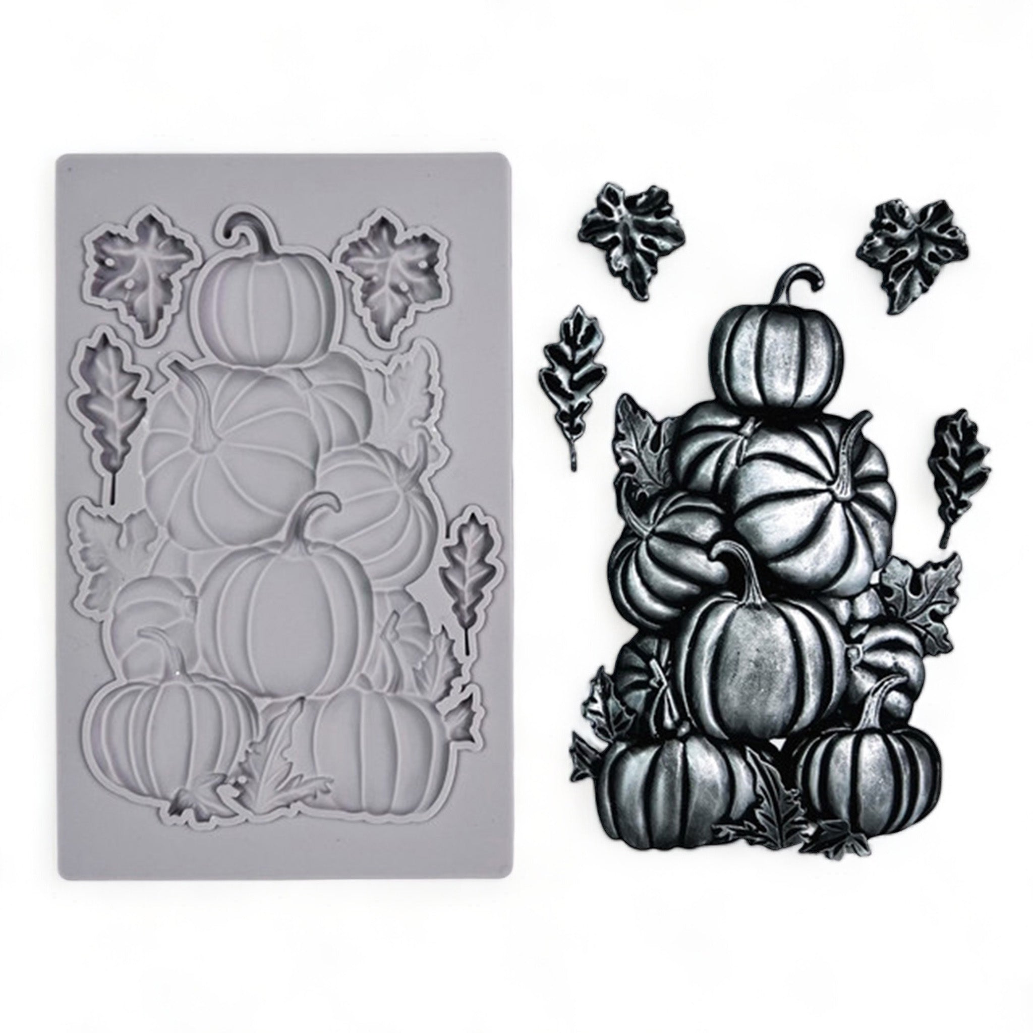 A grey silicone mold and silver colored casting of a stack of pumpkins and 4 small loose leaves are against a white background.