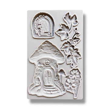 A light grey silicone mold featuring a mushroom fairy house, a hobbit style door, and leaves and flowers is against a white background.