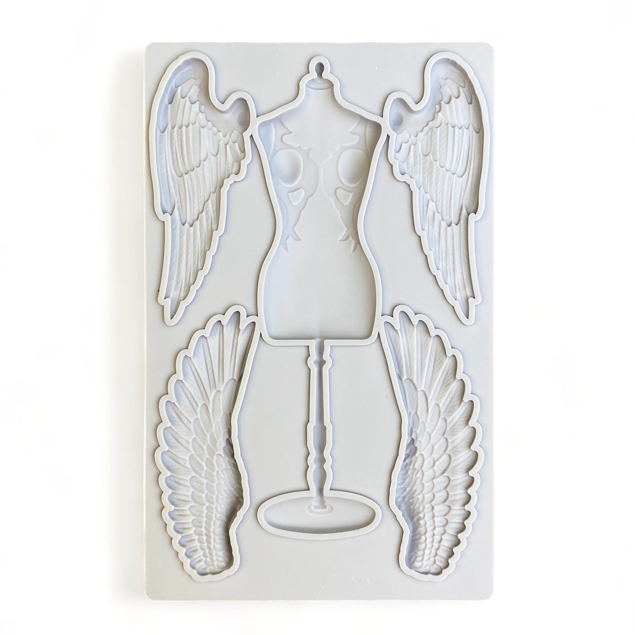 A grey silicone mold of a seamstress dress form and 2 sets of angel wings are against a white background.