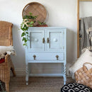 A vintage small end table with 2 doors and a small drawer features Dixie Belle's Bay Breeze Silk All-In-One Mineral Paint.