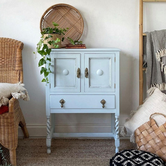 A vintage small end table with 2 doors and a small drawer features Dixie Belle's Bay Breeze Silk All-In-One Mineral Paint.