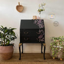 A vintage secretary's desk refurbished by Cherubs Chalks Interiors features Dixie Belle's Black Sands Silk All-In-One Mineral Paint and a dainty purple floral rub-on transfer.
