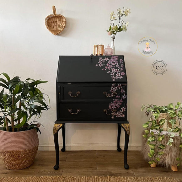 A vintage secretary's desk refurbished by Cherubs Chalks Interiors features Dixie Belle's Black Sands Silk All-In-One Mineral Paint and a dainty purple floral rub-on transfer.