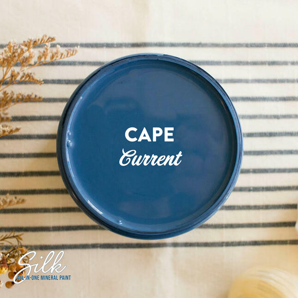 An arial view of an open container of Dixie Belle Paint Company's Cape Current Silk All-In-One Mineral Paint is shown with white text reading Cape Current.