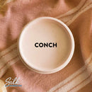 An arial view of an open container of Dixie Belle Paint Company's Conch
Silk All-In-One Mineral Paint is shown with black text reading Conch.