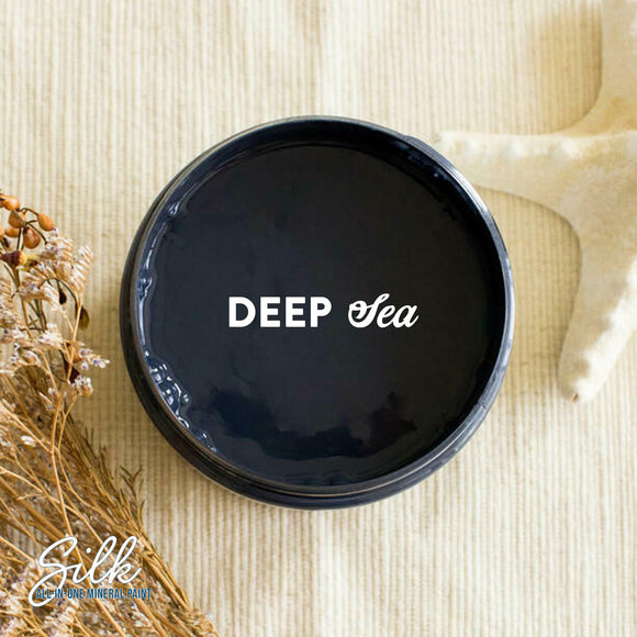 An arial view of an open container of Dixie Belle Paint Company's Deep Sea Silk All-In-One Mineral Paint is shown with white text reading Deep Sea.