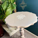 Small white table with decorative design on a marble surface, with 'TLC Vintage' branding in the background.