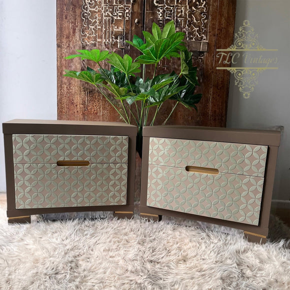 Two wooden dressers with patterned doors and gold handles on a textured surface.