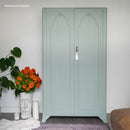 Light green wardrobe with decorative elements in a room setting.