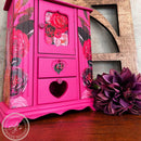 A vintage small table top jewelry armoire refurbished by AJ's Vintage Design has red flower rub-on transfers and features Dixie Belle's Prickly Pear Silk All-In-One Mineral Paint.