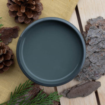 An arial view of an open container of Dixie Belle Paint Company's Soky Mountain All-In-One Silk Paint is on a wood table with pine cones, tree bark, and pine sprigs.