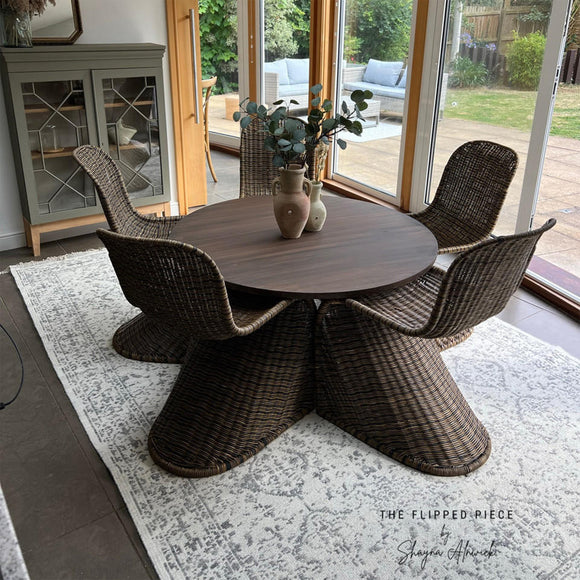 A dark brown wood table and 5 wicker chairs refurbished by The Flipped Piece features Dixie Belle's Umber Silk All-In-One Mineral Paint.