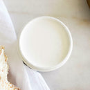 An arial view of an open container of Dixie Belle Paint Company's Whitecap All-In-One Silk Paint is on white material.