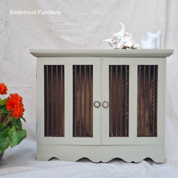 Light gray cabinet with wooden panels and decorative items on a white background