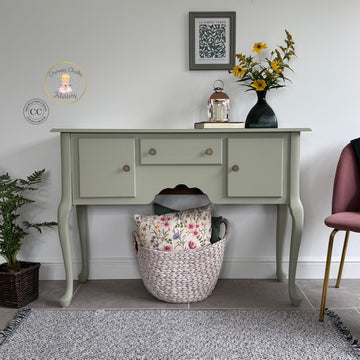 Light green console table with decorative items against a white wall.