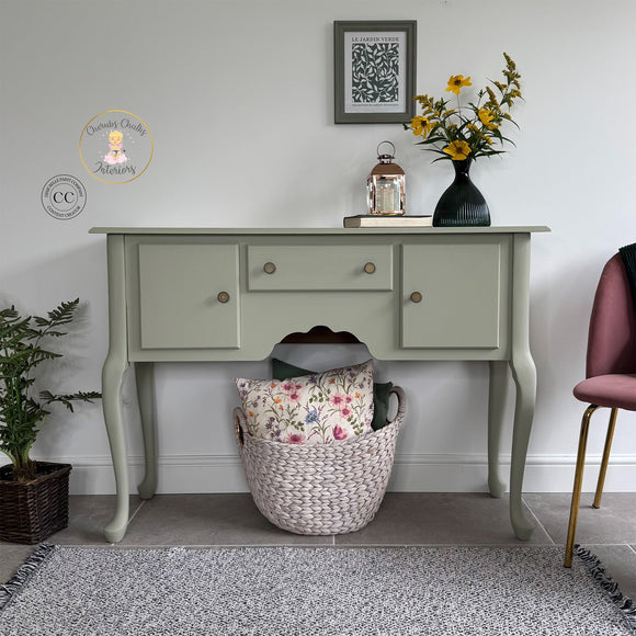Light green console table with decorative items against a white wall.