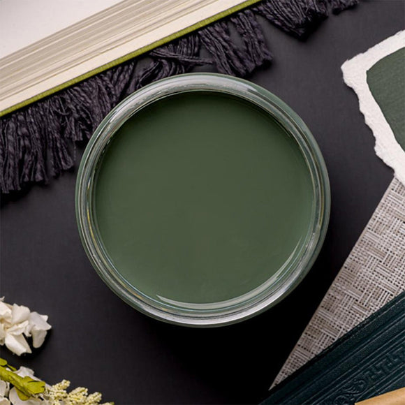 An arial view of an open container of Dixie Belle Paint Company's Blue Grass Chalk Mineral Paint is on a black table with other items.