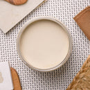 An arial view of an open container of Dixie Belle Paint Company's Ecru Chalk Mineral Paint is on a white lattice table with other items.