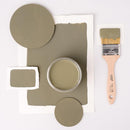 A paint brush, paper, and round wood samples of Dixie Belle's Thicket Chalk Mineral Paint are against a white background.