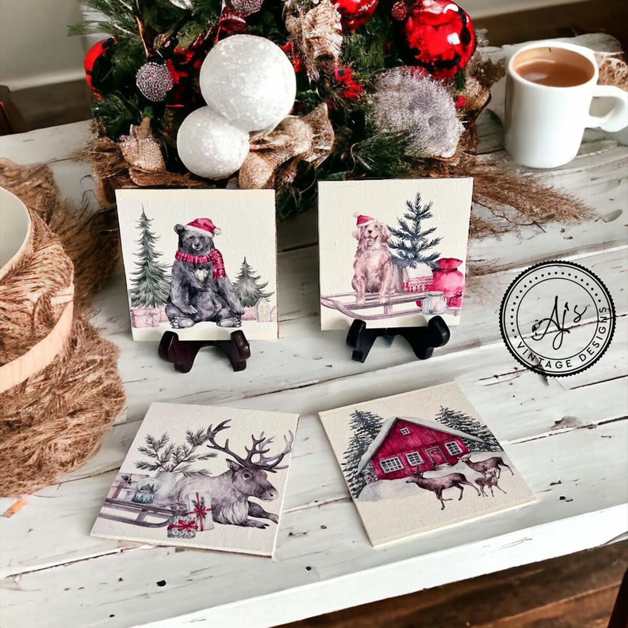 Four small square tiles created by Aj's Vintage Designs are painted white and feature Belles & Whistles' Frosty Forest Friends A4 rice paper on them.