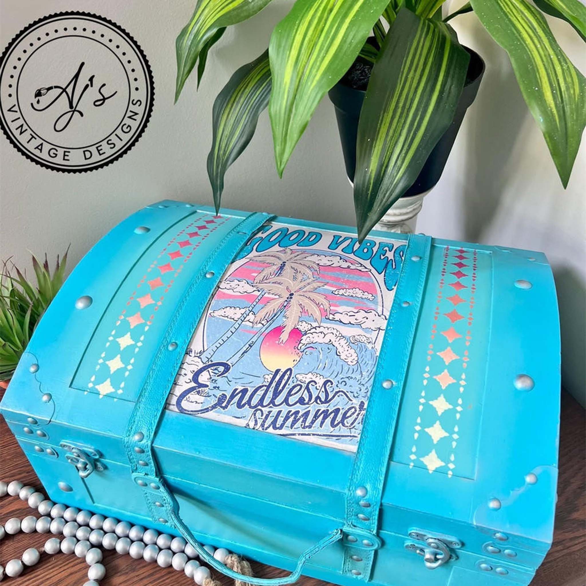 A vintage suitcase refurbished by AJ's Vintage Designs is painted sky blue and features Belles and Whistles' Endless Summer A4 rice paper on it.