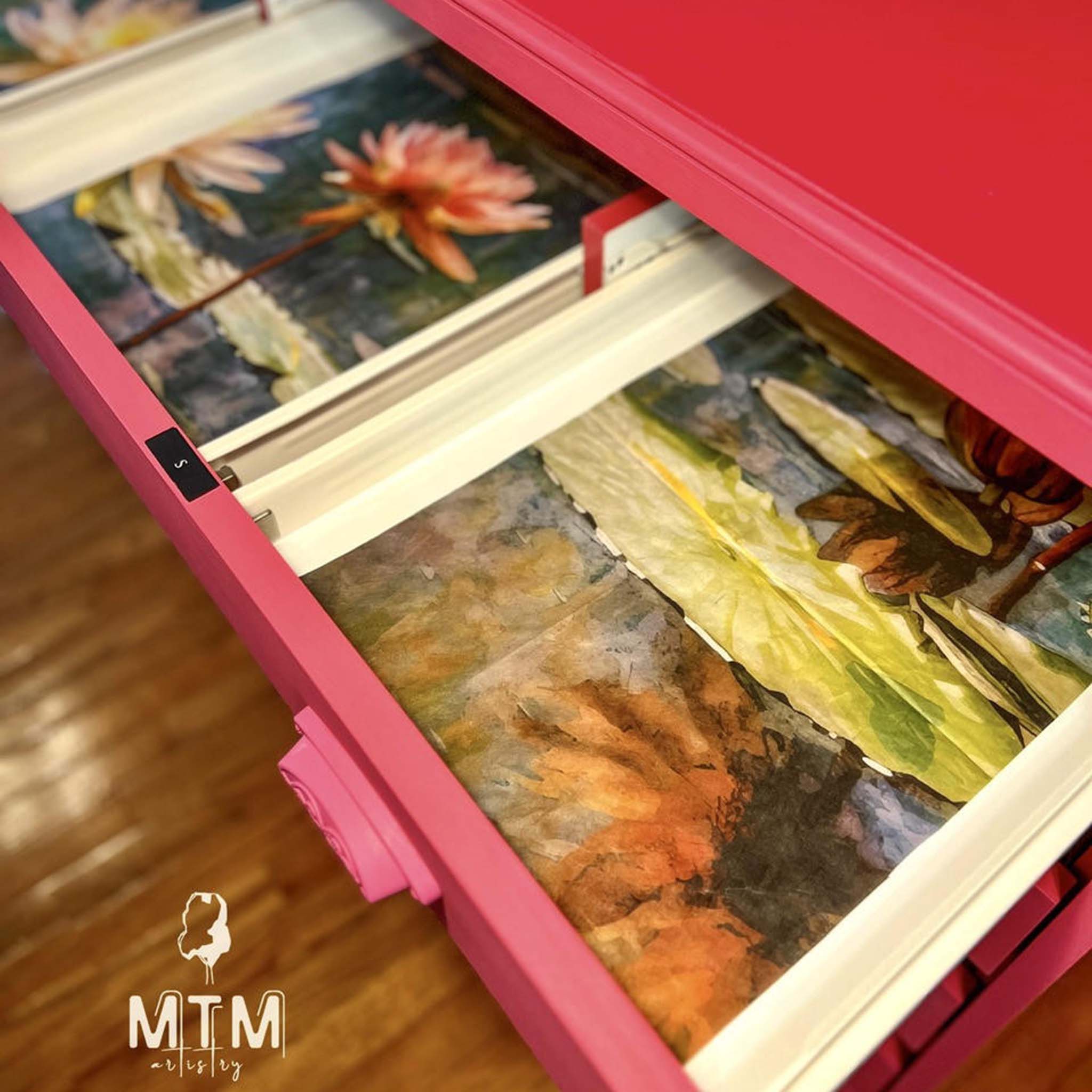 A close-up of an open pink dresser drawer refurbished by MTM Artistry features Belles and Whistles' Lily Pads A1 rice paper inside.