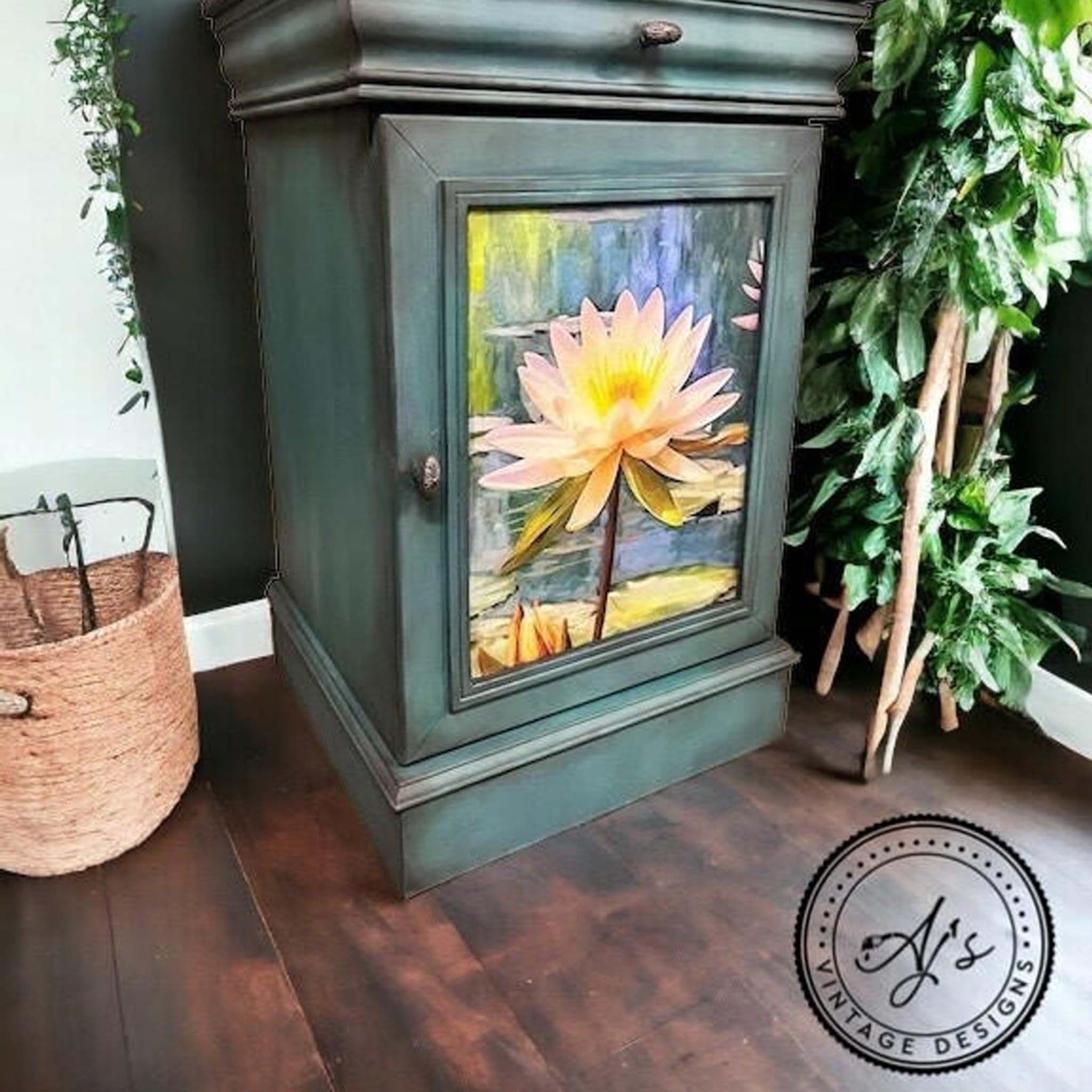 A vintage nightstand with storage cubby refurbished by AJ's Vintage Designs is painted green-blue with black glaze details and features Belles and Whistles' Lily Pads A1 rice paper on the inlay of its door.