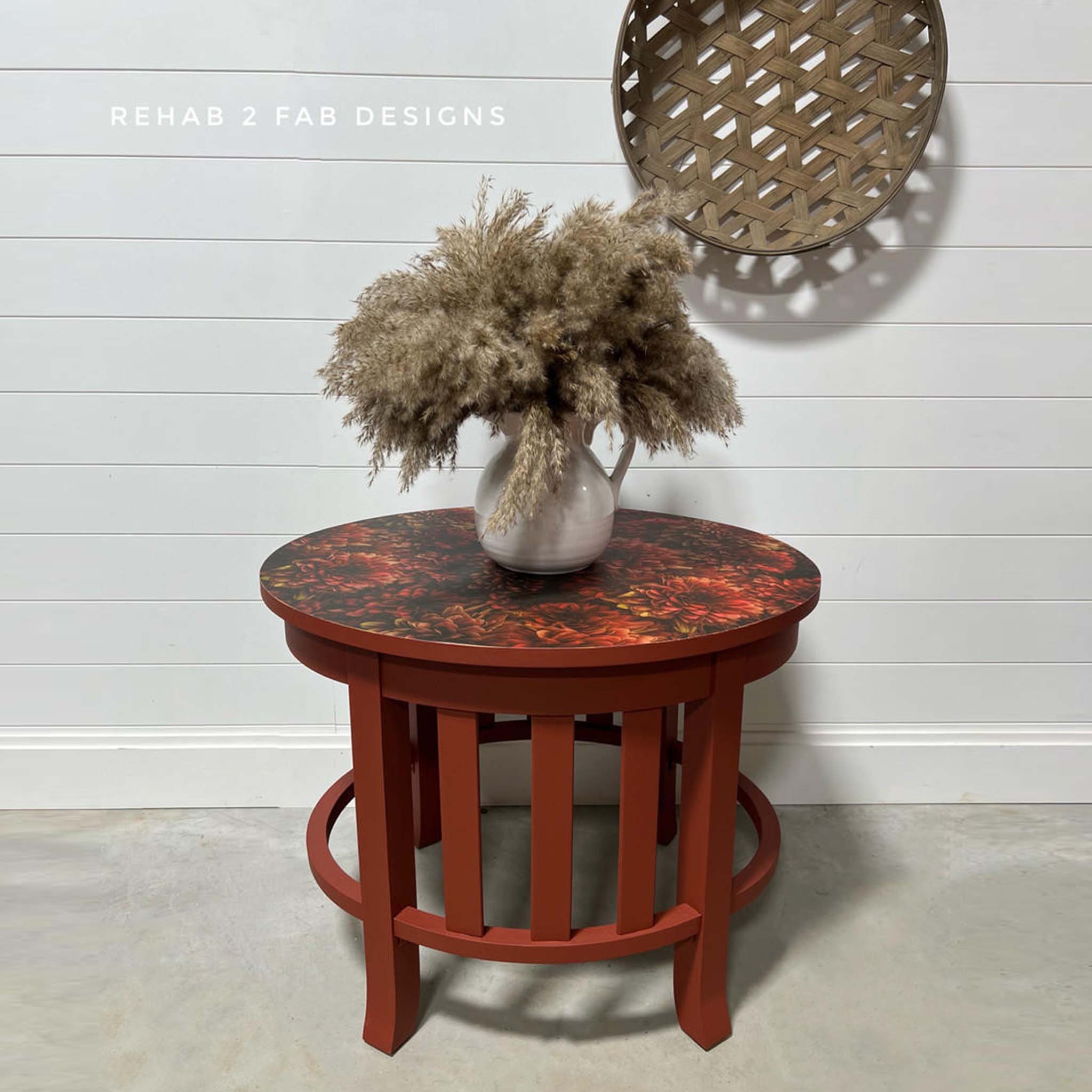 A small round side table is painted burnt orange and features Belles and Whistles' Moody Mums A1 rice paper on the table top.