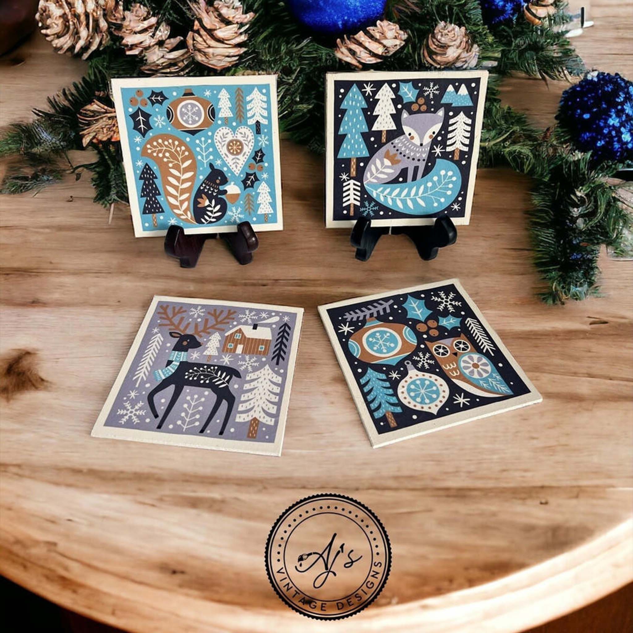 Four small square tiles created by Aj's Vintage Designs are painted white and feature Belles & Whistles' Nordic Noel rice paper on them.