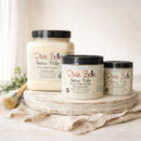 Three containers of Dixie Belle Paint Company's Gator Hide in 3 sizes (32, 16, and 8 fluid ounces) on a wooden tray with a white background.