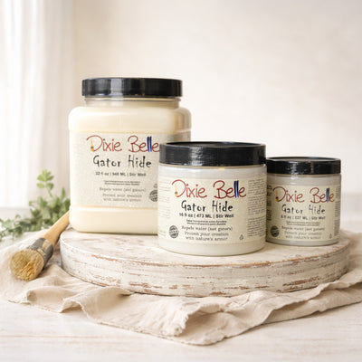 Three containers of Dixie Belle Paint Company's Gator Hide in 3 sizes (32, 16, and 8 fluid ounces) on a wooden tray with a white background.