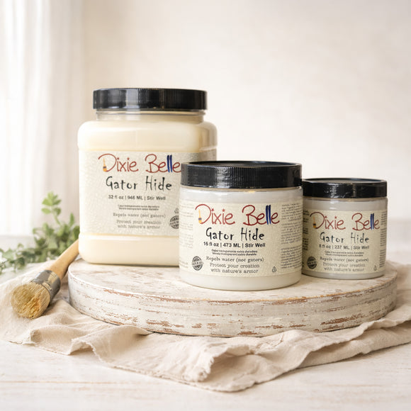 Three containers of Dixie Belle Paint Company's Gator Hide in 3 sizes (32, 16, and 8 fluid ounces) on a wooden tray with a white background.