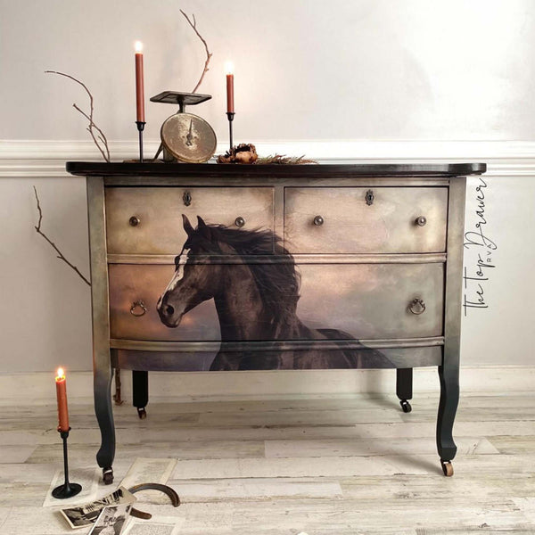 A vintage dresser refurbished by The Top Drawer is painted a blend of beige down to black with a natural wood stained top and features Belles & Whistles Majestic Horse A1 rice paper on its drawers.