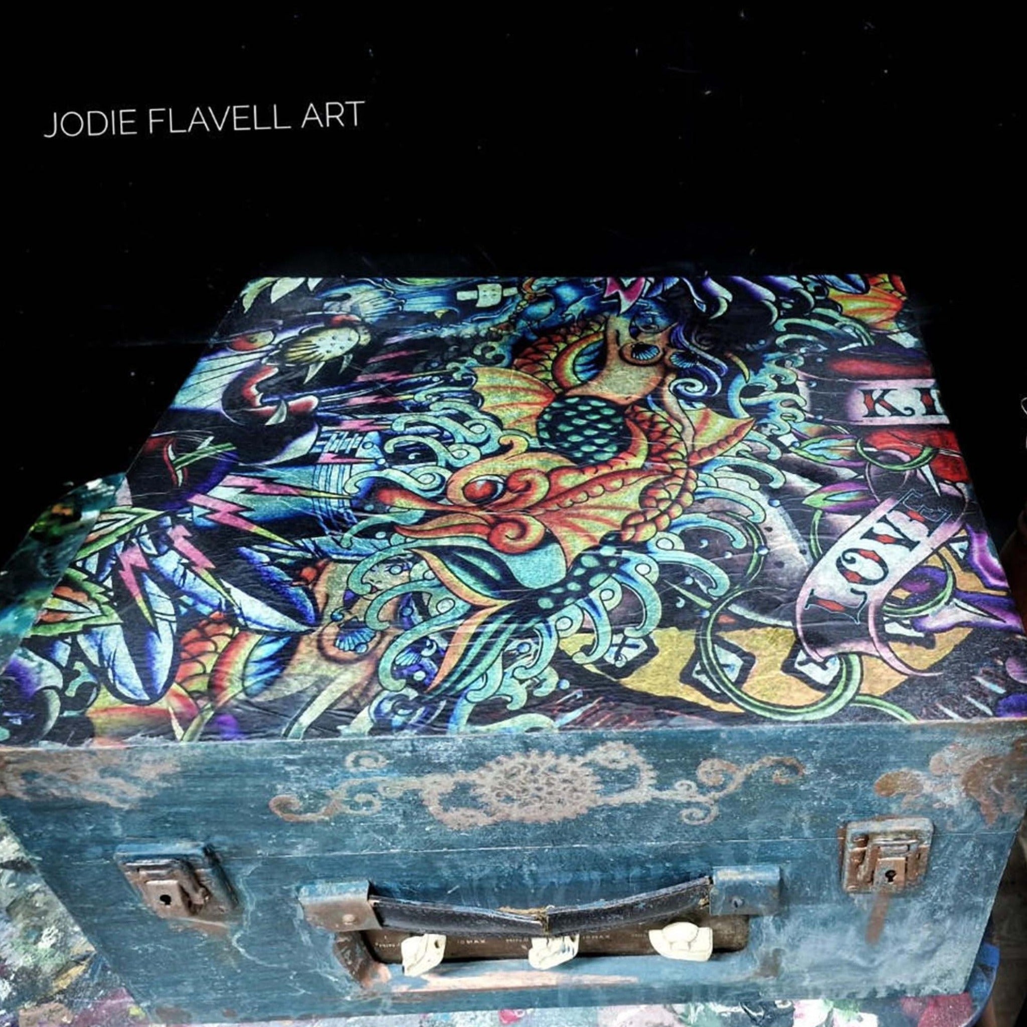 A vintage luggage box refurbished by Jodie Flavell Art is painted a distressed blue and features Belles & Whistles Vintage Tattoo A1 rice paper on it.