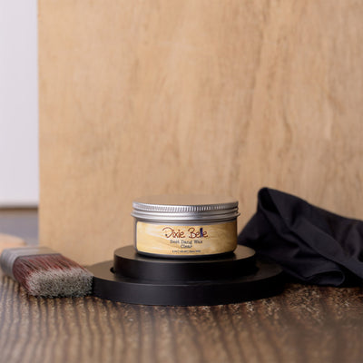 Jar of Dixie Belle wood finish on a wooden surface with a brush and cloth.