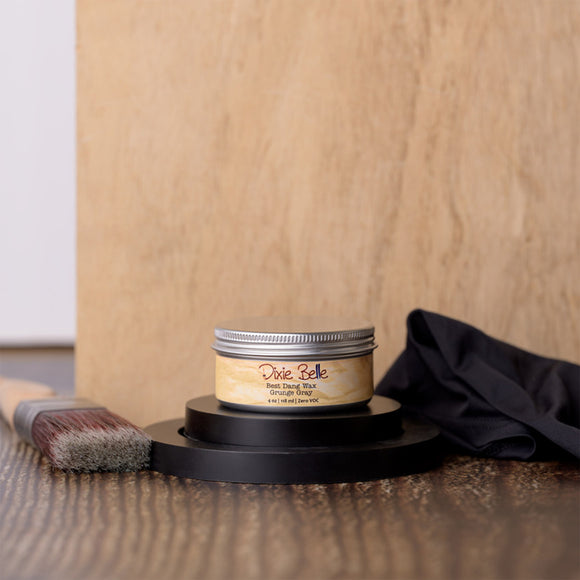 Jar of Dixie Belle wood finish on a wooden surface with a brush and cloth.