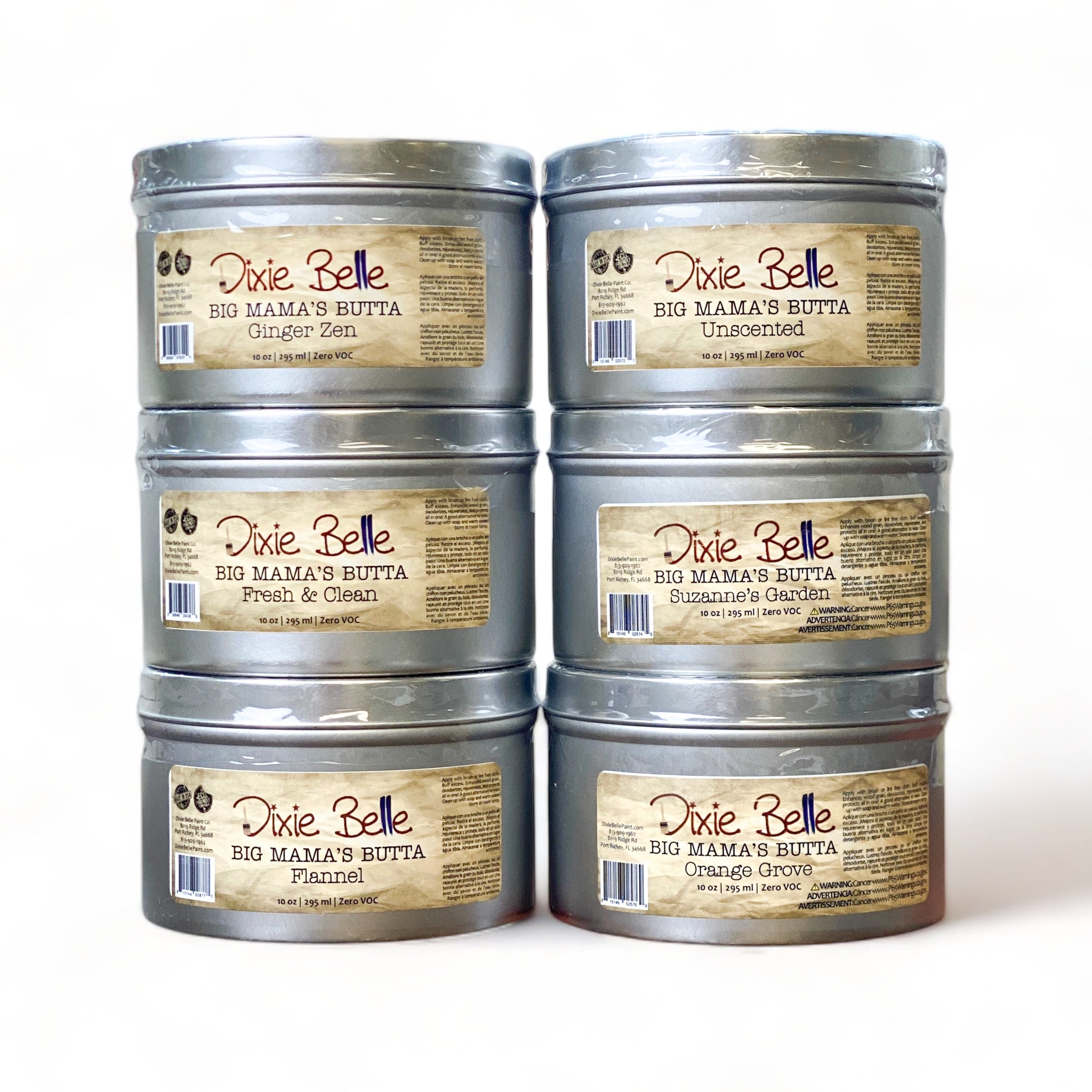 Two stacks of six 10 ounce tins of Dixie Belle's Big Mama's Butta in scents of Ginger Zen, Unscented, Fresh & Clean, Suzanna's Garden, Flannel, and Orange Grove are against a white background. 