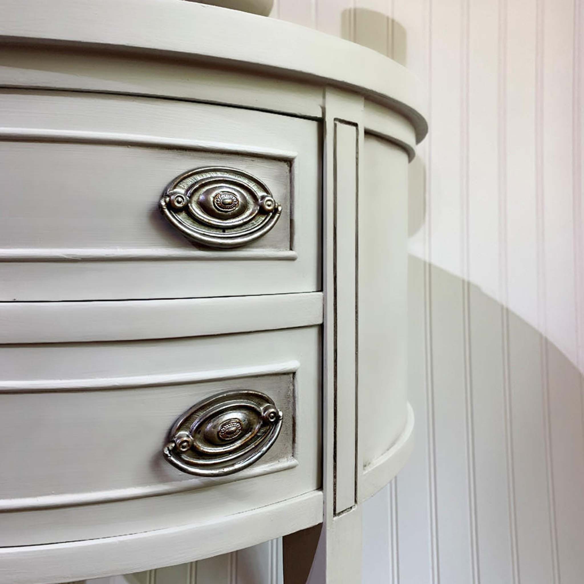 A close-up view of a vintage end table is painted light grey and features Dixie Belle Paint's Black Glaze to accent inlays and crevices.