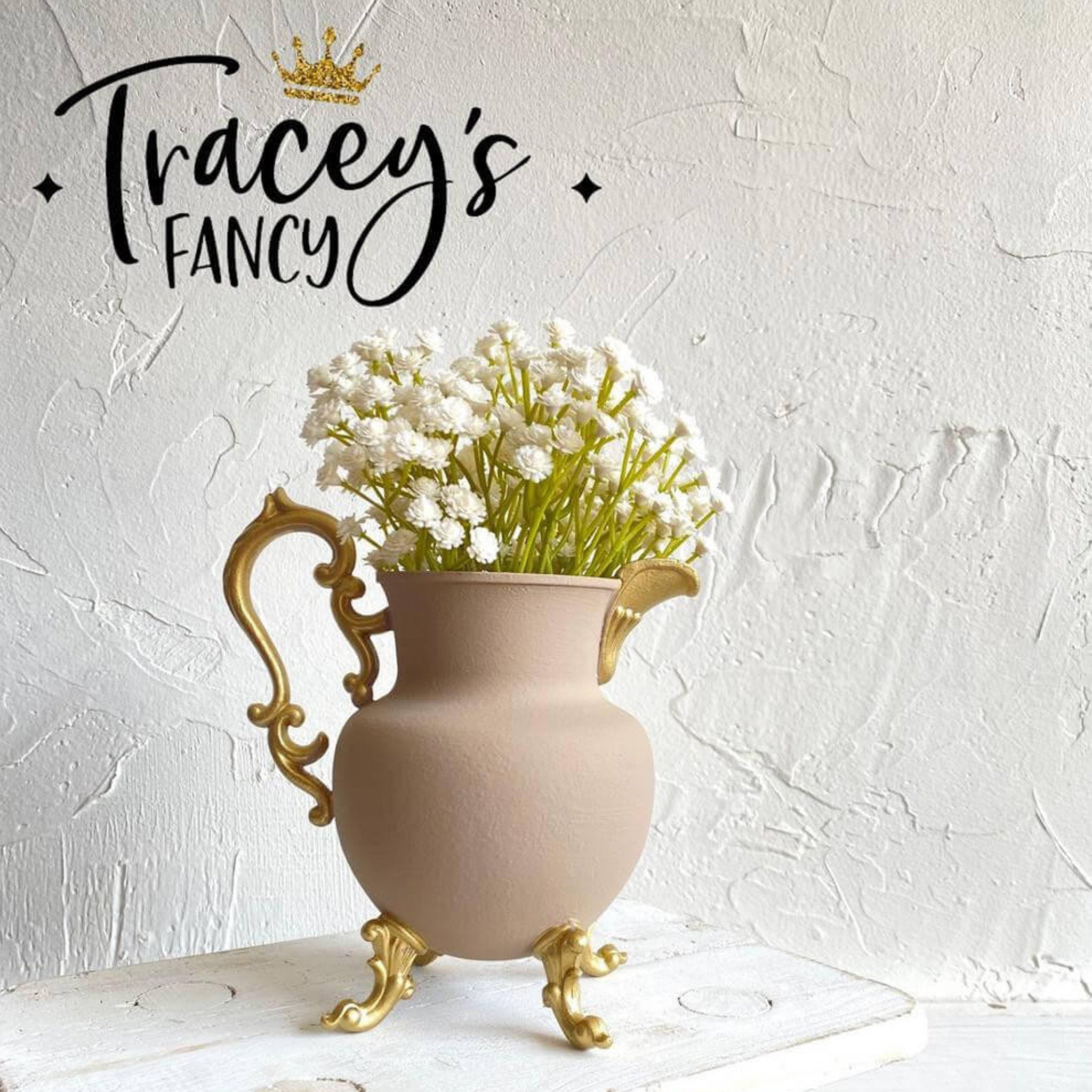 A ceramic watering vase refurbished  by Tracey's Fancy is painted in Dixie Belle's Cobblestone chalk mineral paint with gold-painted legs, handle, and pour spout .