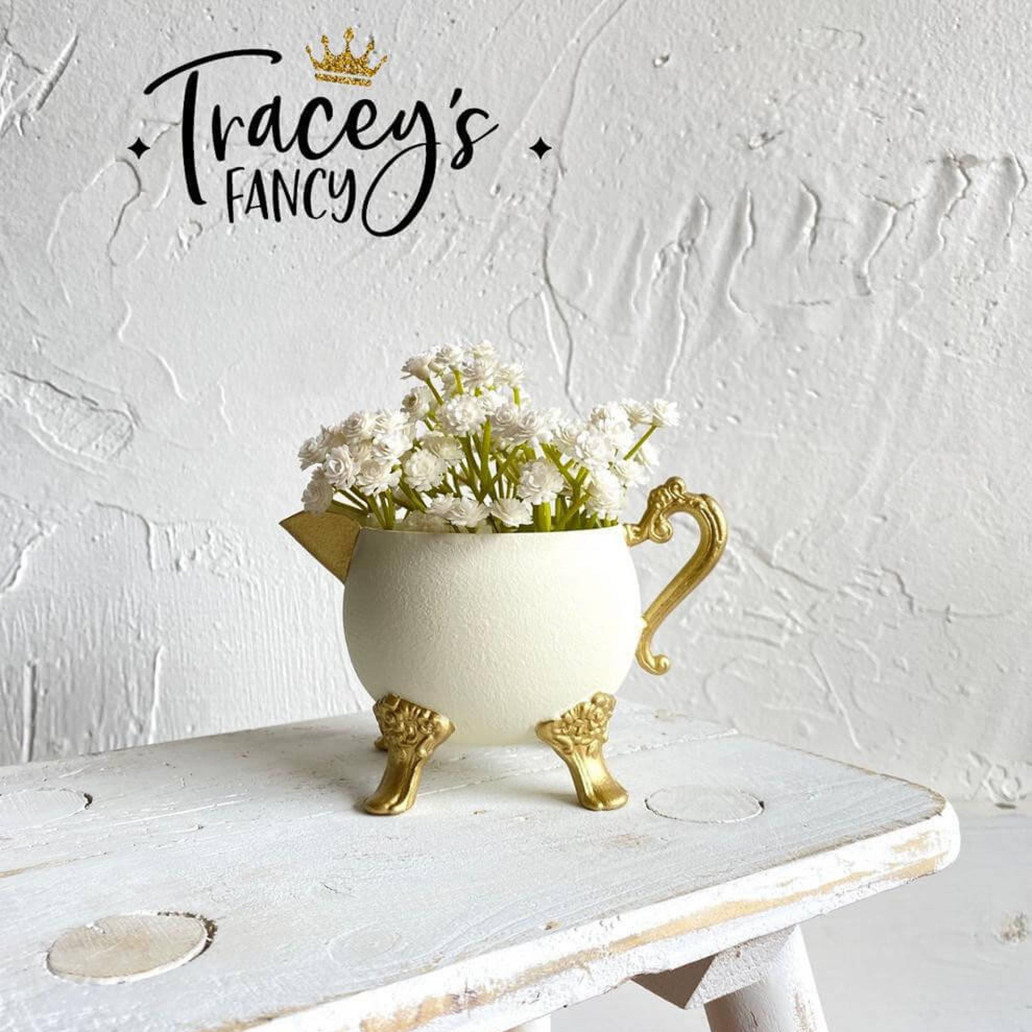 A small ceramic vase turned into a watering vessel created by Tracey's Fancy is painted in Dixie Belle's Cucumber Ice chalk mineral paint and has gold painted legs, handle and spout.