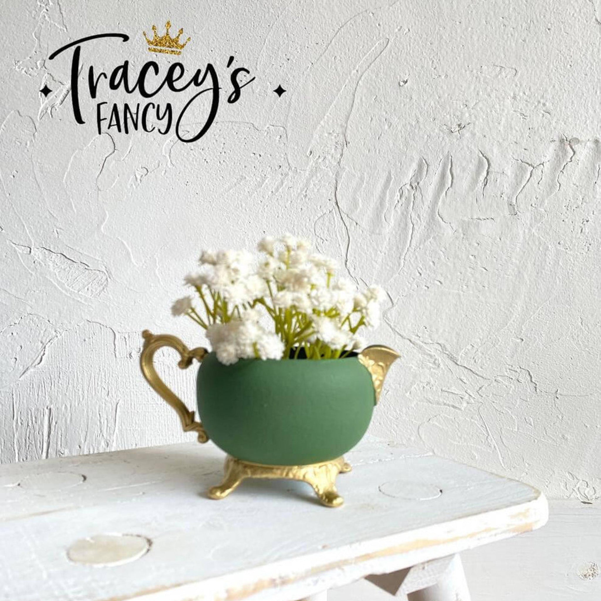 A small ceramic vase created by Tracey's Fancy is painted in Dixie Belle's English Ivy and has gold-painted legs, handle, and spout.
