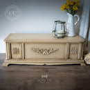 A small vintage table storage box refurbished by Bow Tie Treasures is painted light sandy brown and features Dixie Belle Paint's Van Dyke Brown Glaze on it to accent detailed areas.