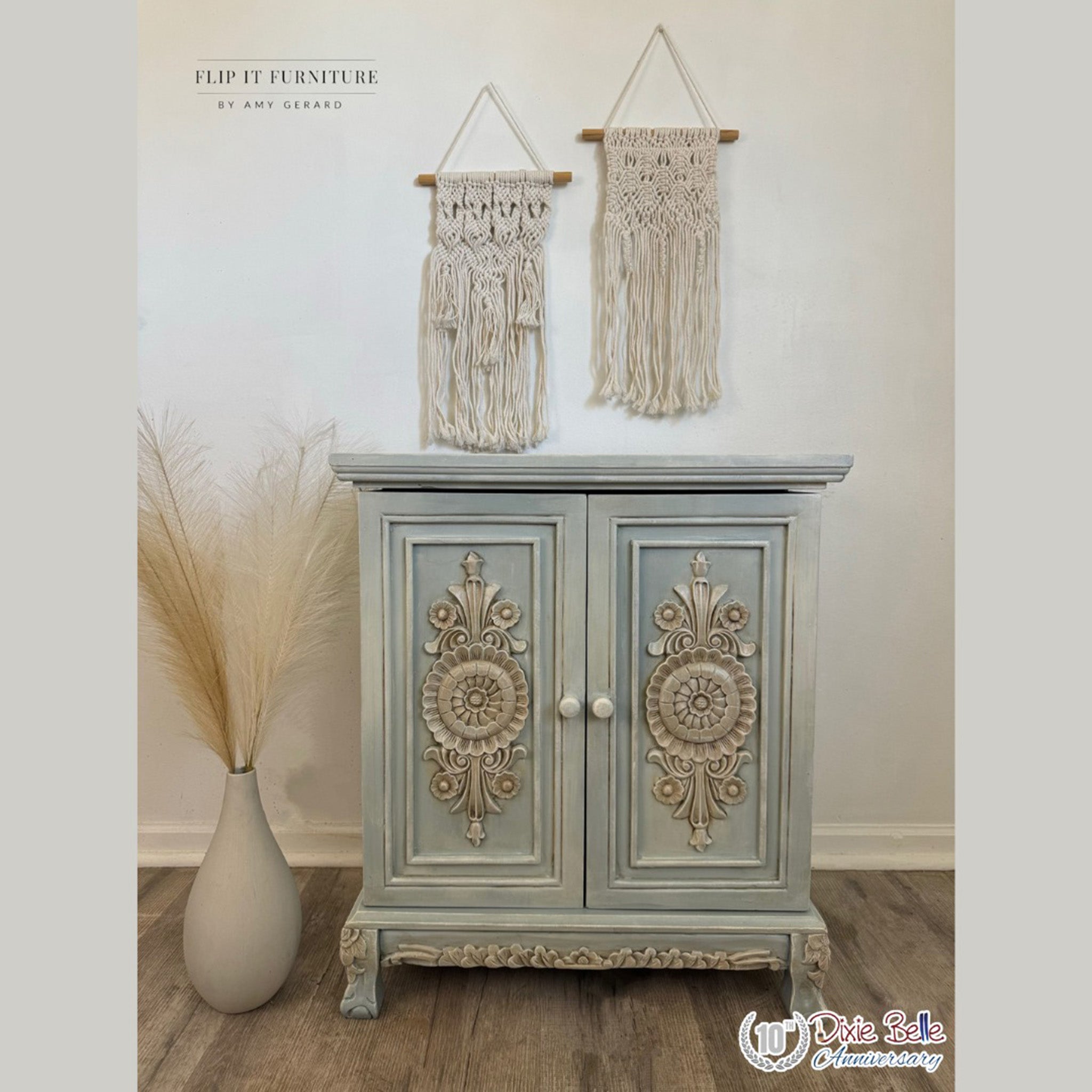 A vintage small buffet cabinet refurbished by Flip It Furniture by Amy Gerard is painted pale blue with light gray ornate accent pieces. The accent pieces are detailed using Dixie Belle Paint's Van Dyke Brown Glaze.