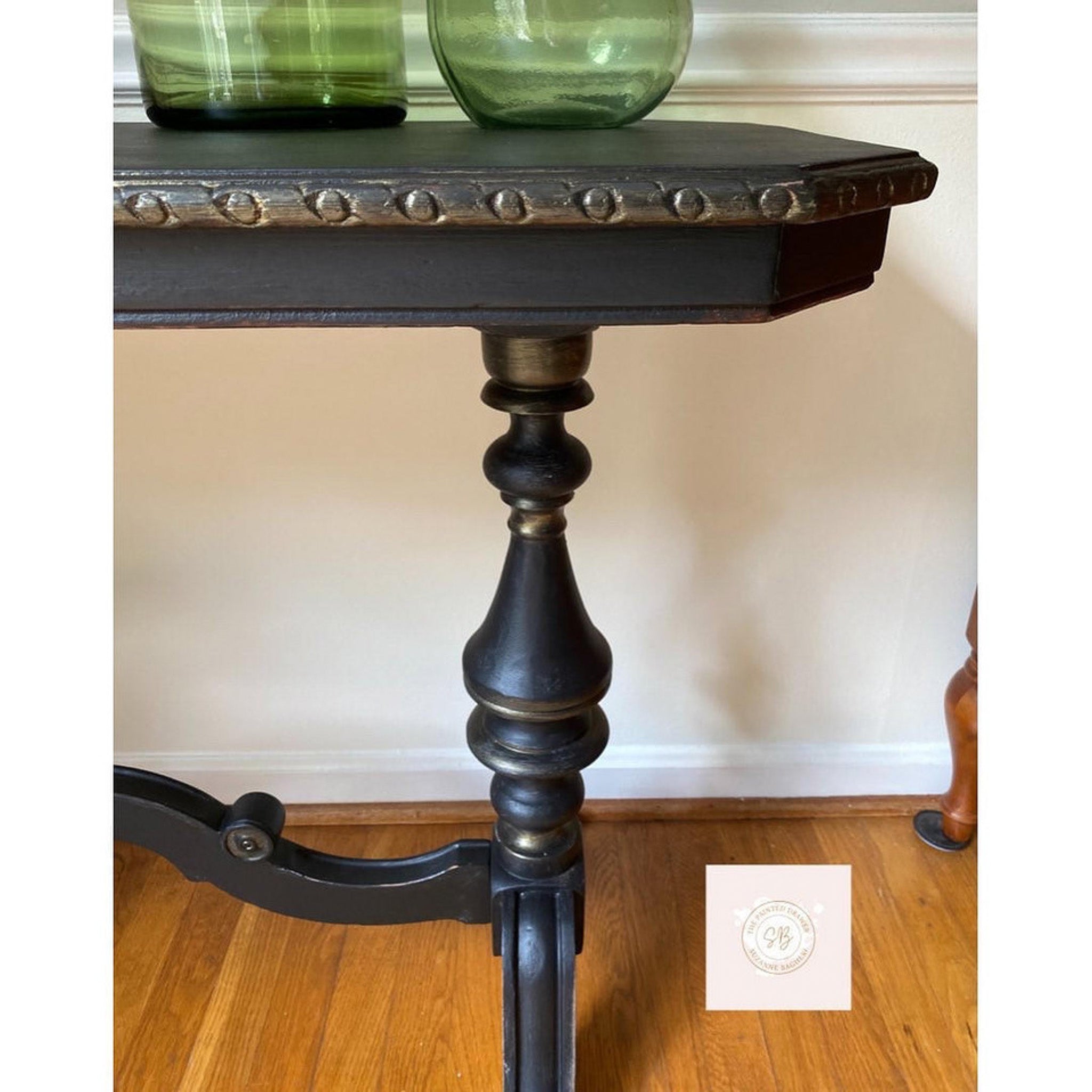 A vintage entryway table refurbished by The Painted Drawer is painted black and features Dixie Belle Paint's Gold Shimmer Glaze to accent edges and details.