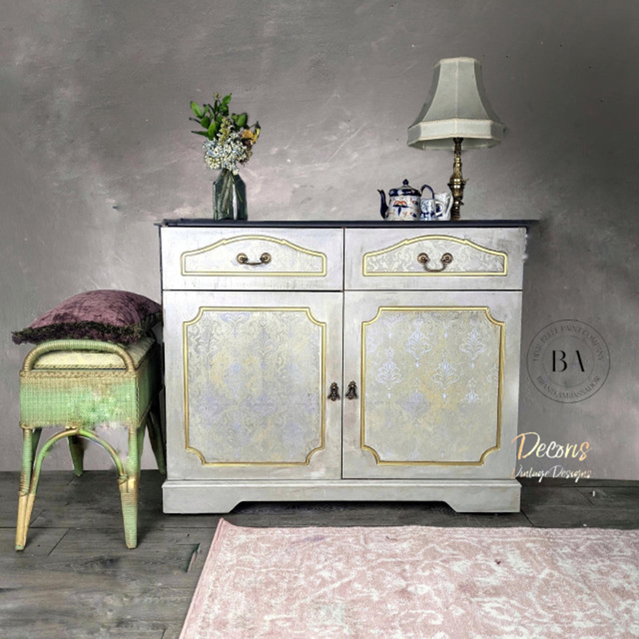 A small buffet cabinet is painted silver and features Dixie Belle Paint's Gold Shimmer glaze on inlay details of its 2 doors and 2 drawers.