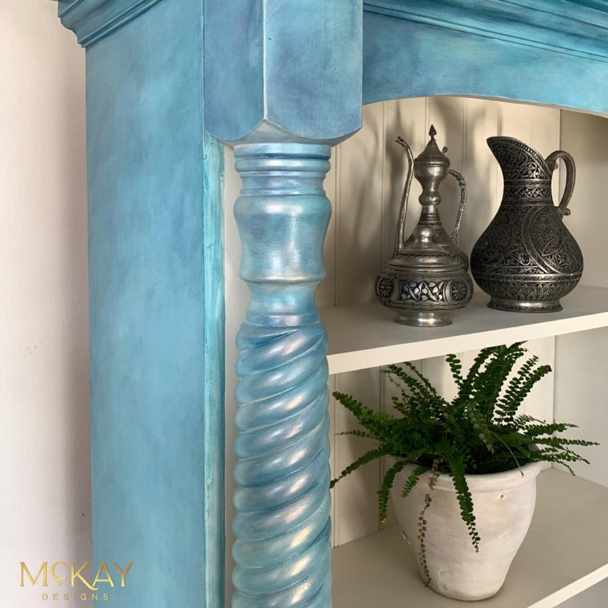 A close-up view of a vintage hutch refurbished by McKay Designs is painted light blue and features Dixie Belle Paint's Pearlescent Glaze to highlight a front spiraled accent post.