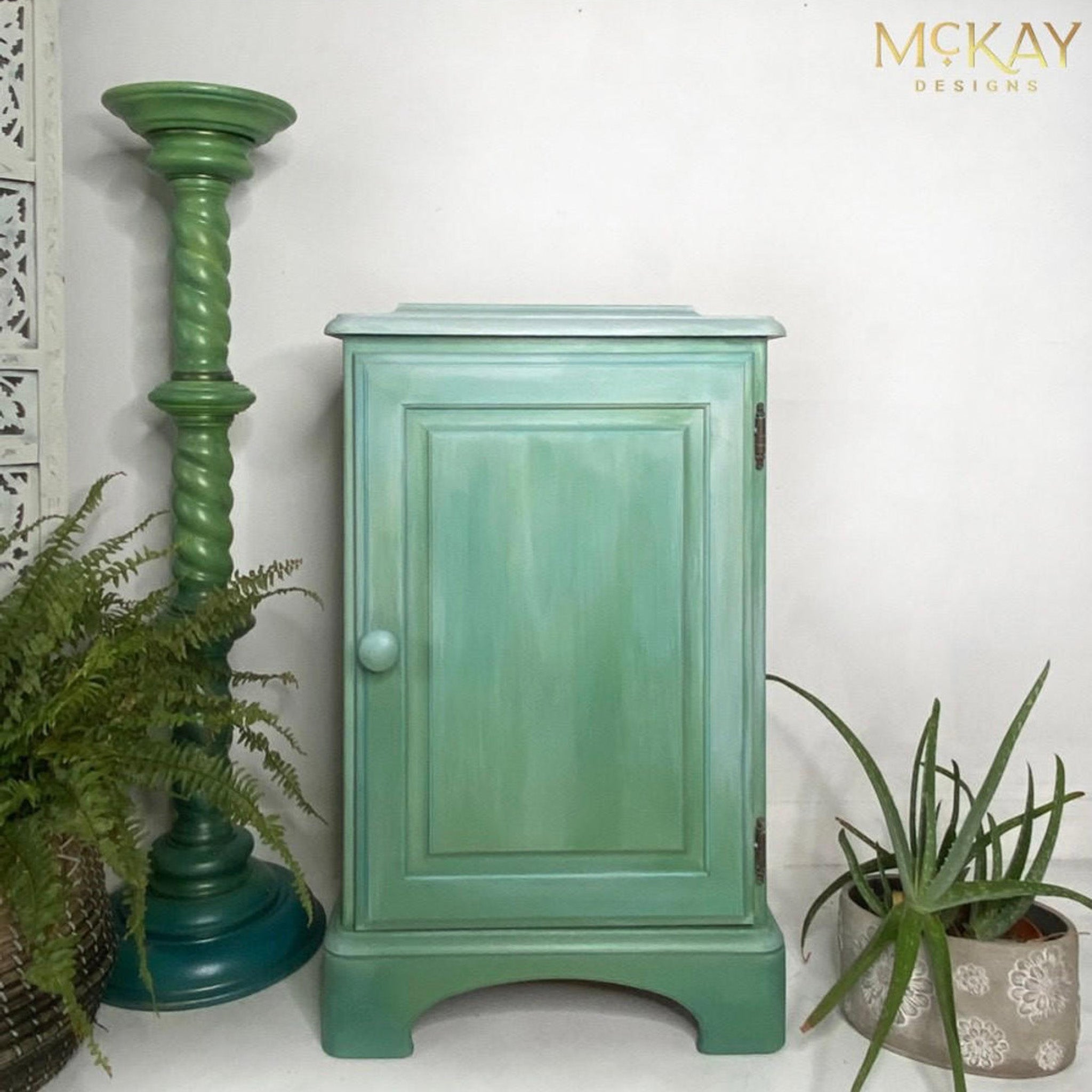 A vintage night stand with a store door refurbished by McKay Designs is painted light green and features Dixie Belle Paint's Whitewash Glaze as an ombre accent on the top half.