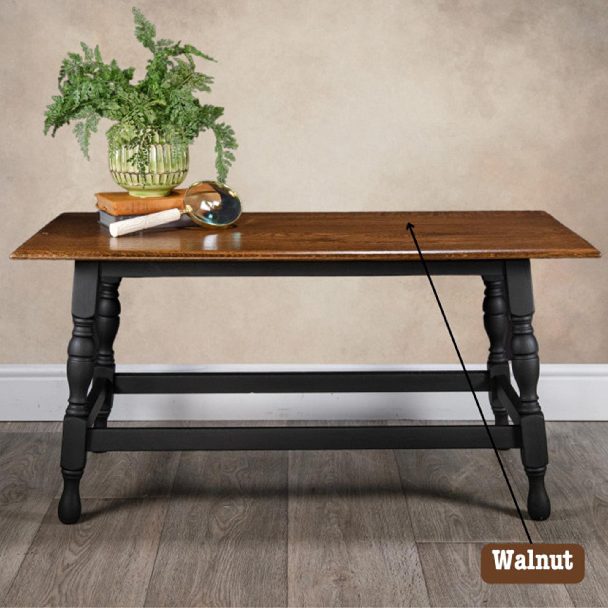 A wood kitchen table features Dixie Belle Paint's No Pain Gel Stain in Walnut on its tabletop. The legs of the table are painted black.