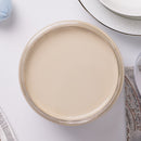 Jar of cream paint on a white surface with a mirror and towel in the background